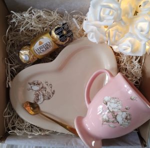 Box de regalo, con chocolatera color rosada, cuchara dorada de diseño, plato en forma de corazón, y bombones Ferrero Rocher de tres unidades.