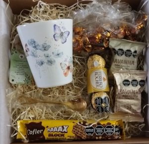 Box de cumpleaños. Taza con cucharita dorada, de diseño. Acompañada de golosinas de primeras marcas.